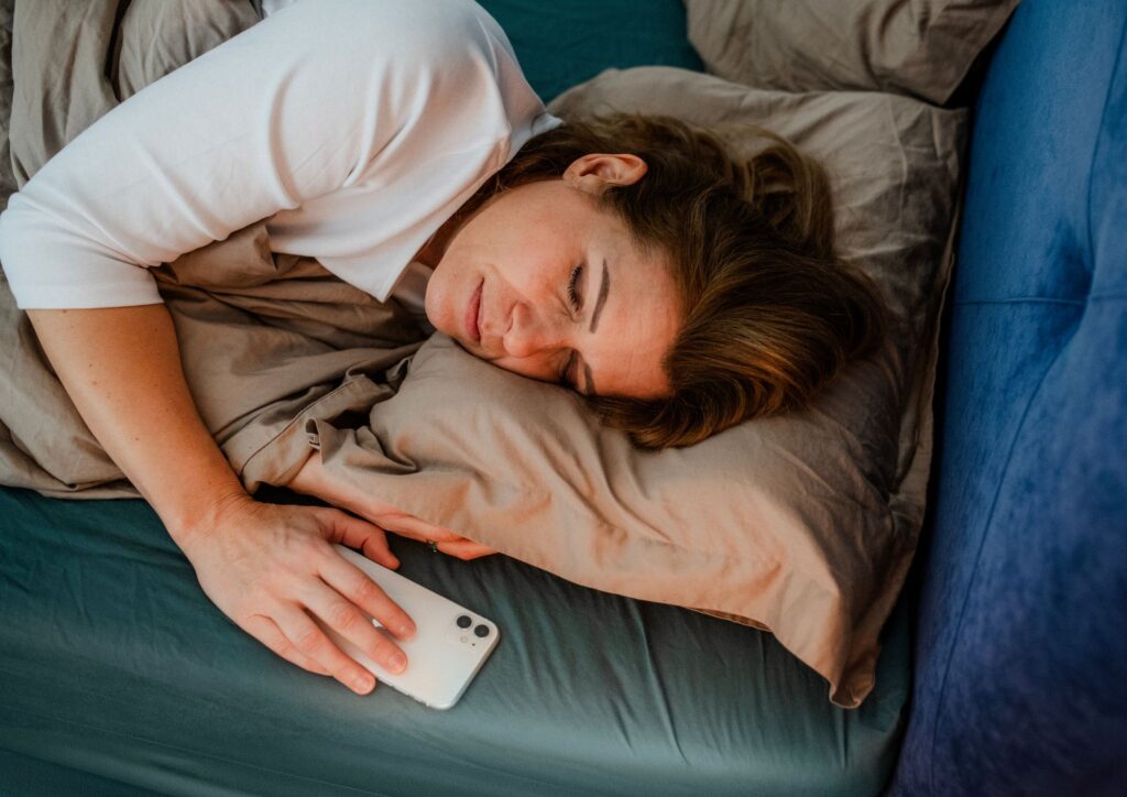 Donna a letto col cellulare mentre cerca di dormire