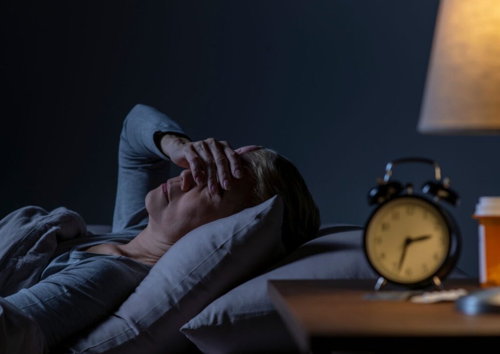 donna matura a letto al buio ancora sveglia mentre aspetta di addormentarsi